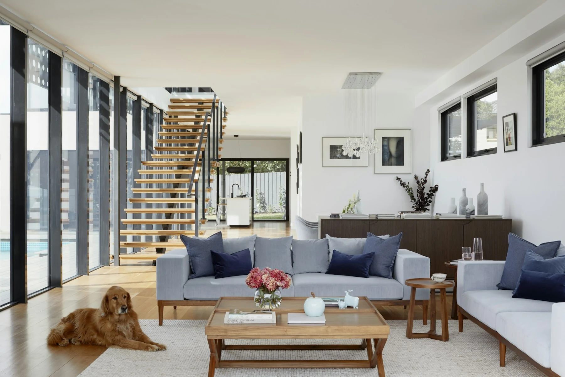 An open living room with a staircase and tall windows